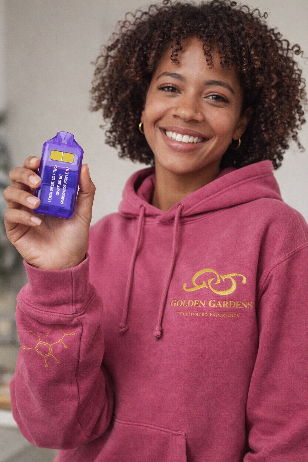 Woman wearing a pink Golden Gardens hoodie, holding Slim Vaporizer.